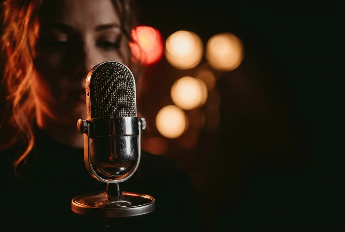 A vintage chrome stage microphone lit in warm amber light