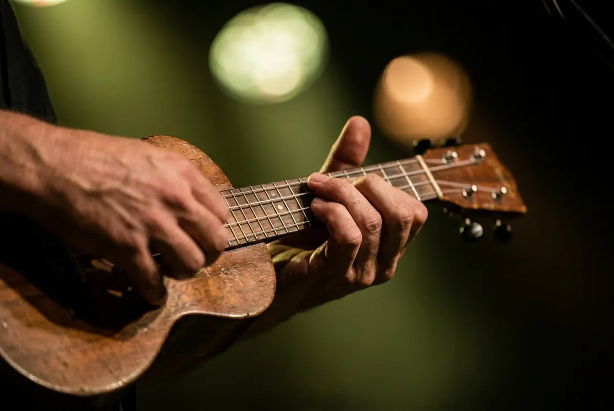 Hands strumming a wooden ukulele, lit in soft green stage light